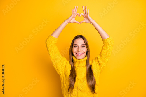 Portrait of positive cheerful girl want celebrate valentine cupid day date with her boyfriend make heart from fingers passionate love sign wear soft jumper isolated yellow color background