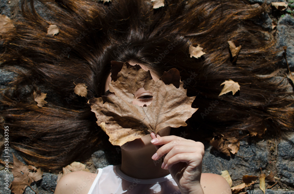Teenage girl lying on floor with leaves in her hair Stock Photo | Adobe ...