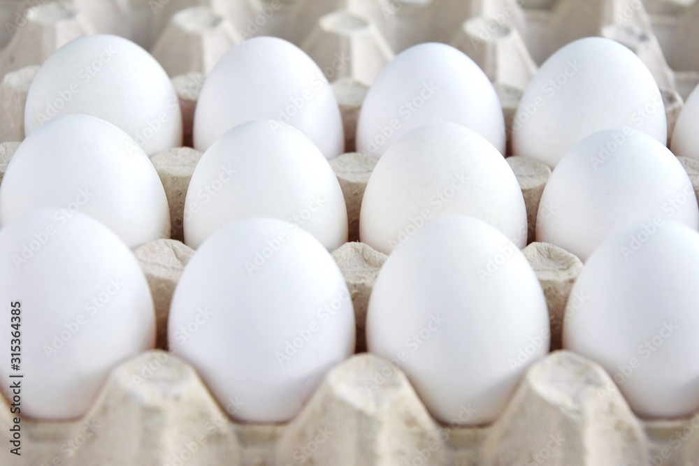 Row of white chicken eggs in cardboard container. healthy protein breakfast. Fresh organic chicken eggs with selective focus. Egg box. Easter preparation. Raw eggs for Easter holiday. Uncooked Row of white chicken eggs in cardboard container. healthy protein breakfast. Fresh organic chicken eggs with selective focus. Egg box. Easter preparation. Raw eggs for Easter holiday. Uncooked