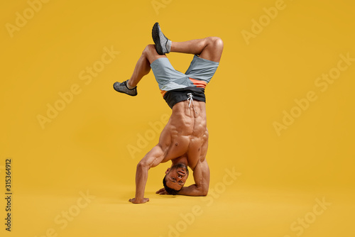 Tablou canvas Muscular young bodybuilder performing handstand stunt