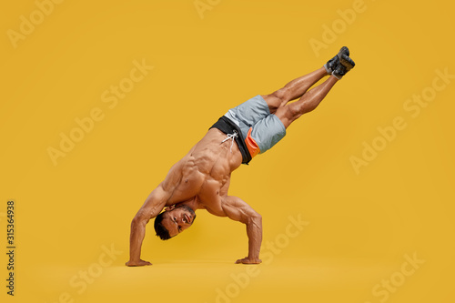 Obraz na plátně Athletic young man performing handstand stunt
