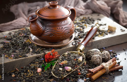 Dry tea leaves on a table in a composition with accessories for tea drinking
