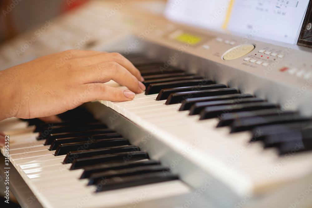 Fototapeta premium Close-up of a music performer's hand playing the piano