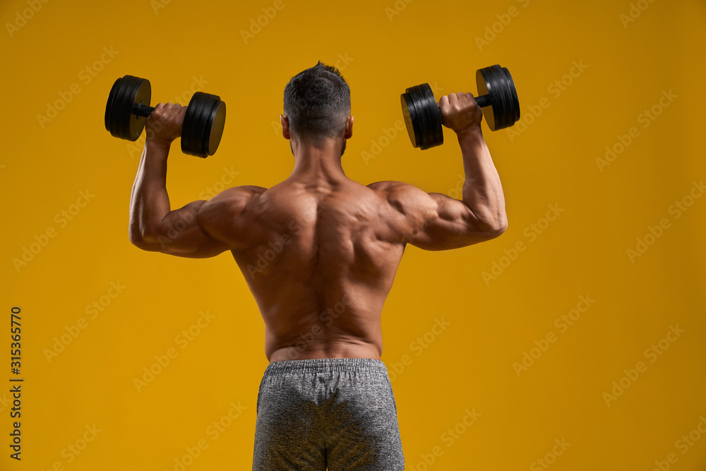 Strong athletic guy doing exercise with dumbbells Strong athletic guy doing exercise with dumbbells
