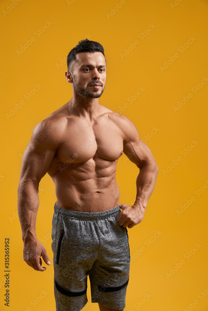 Strong bodybuilder keeping hand on waist