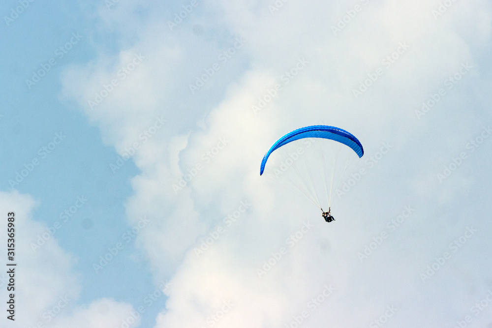 A sportsman flies in the sky in a good suit on a paraglider. Paragliding Sport Concept A sportsman flies in the sky in a good suit on a paraglider. Paragliding Sport Concept