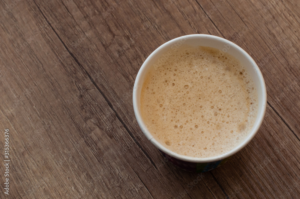 Cappuccino with a delicious foam in a paper cup, top view, coffee to go