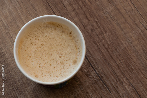 Cappuccino with a delicious foam in a paper cup, top view, coffee to go