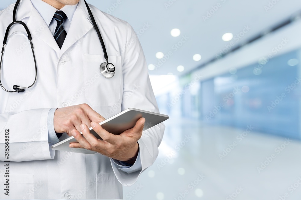 Attractive young male doctor with blurred hospital interior background Attractive young male doctor with blurred hospital interior background