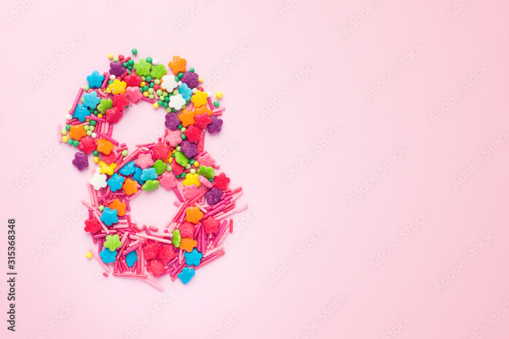 Number 8 in the shape of sweets. March 8 International Women's Day pink background, copy space, flat lay