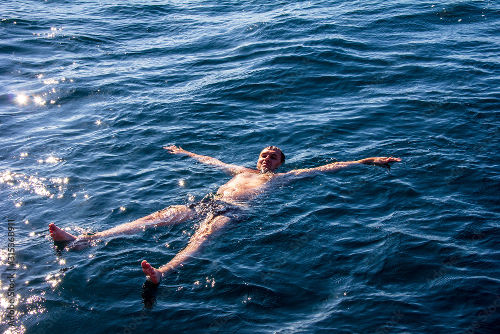 happy man lies on sea water on a warm summer day
