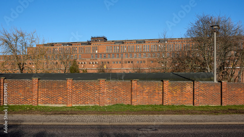 Germany, Saxony-Anhalt, Vockerode: Street view of big old defunct shut down former Vockerode lignite power plant building with brick stone facade, no chimneys and blue sky - concept energy lost place photo