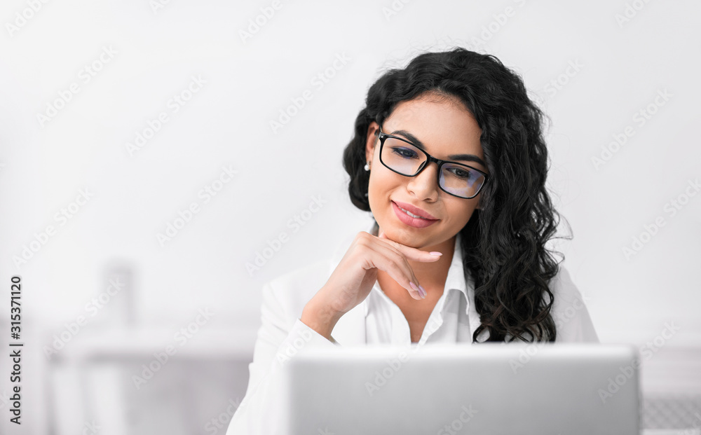 Satisfied hispanic girl manager looking at laptop Satisfied hispanic girl manager looking at laptop