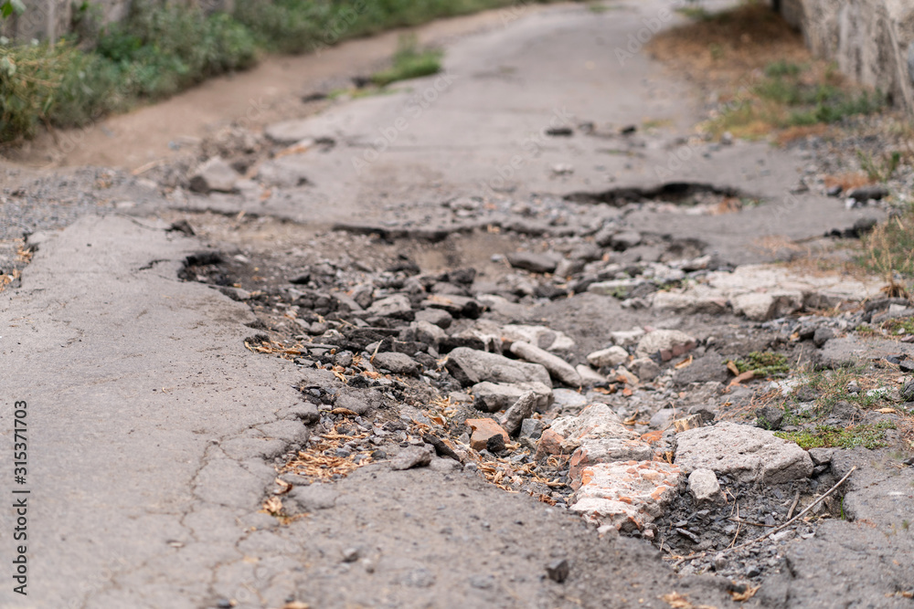 asphalt road destroyed by holes and washed out by water