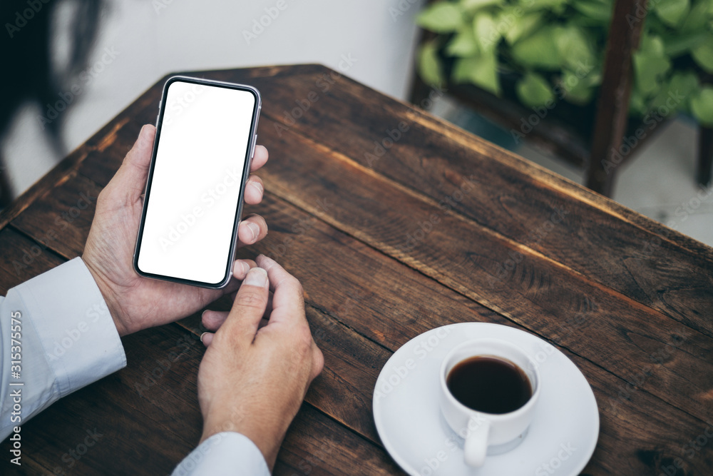 Mockup image blank white screen cell phone.man hand holding texting using mobile on desk at coffee shop.background empty space for advertise text.people contact marketing business,technology Mockup image blank white screen cell phone.man hand holding texting using mobile on desk at coffee shop.background empty space for advertise text.people contact marketing business,technology