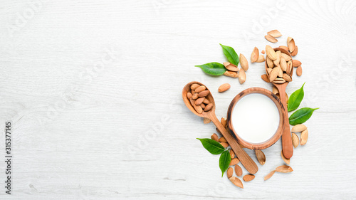 Almond milk and almonds on a white wooden table. Top view. Free space for your text.