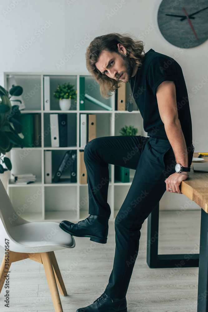 fashionable casual businessman in total black outfit posing in office on  table Stock Photo | Adobe Stock