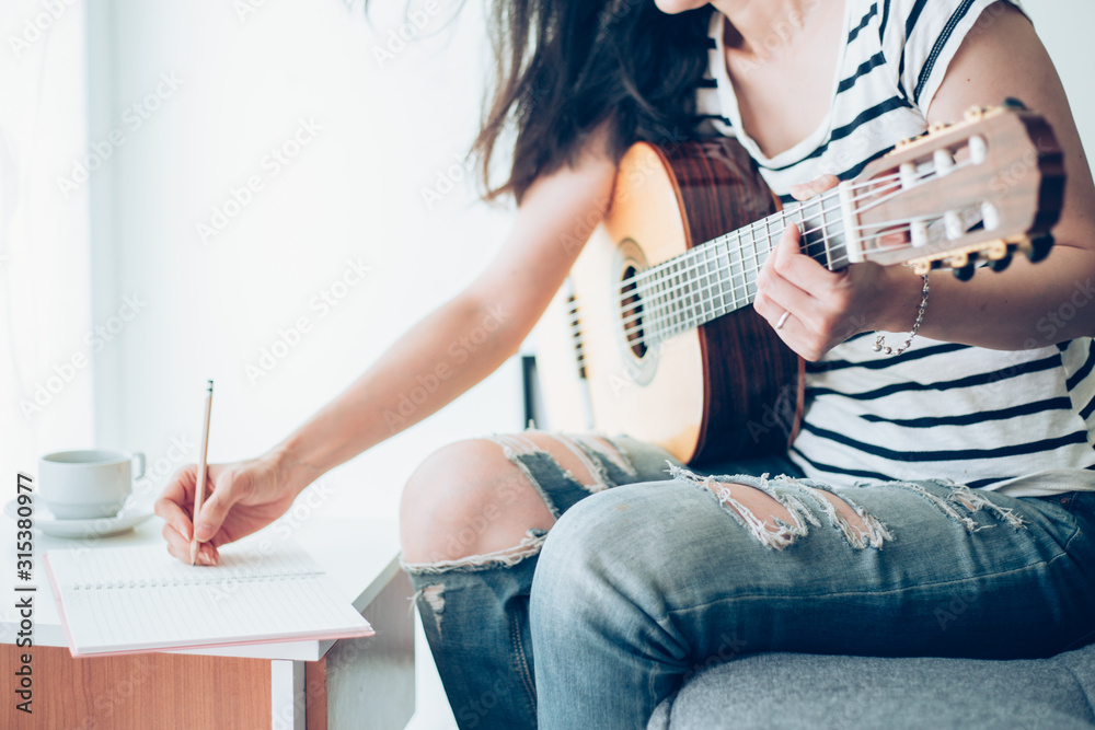 Fototapeta premium artist songwriter thinking writing notes,lyrics in book at studio.man playing live acoustic guitar relax chill.concept for musician creative.composer work process.people relaxing time with instrument