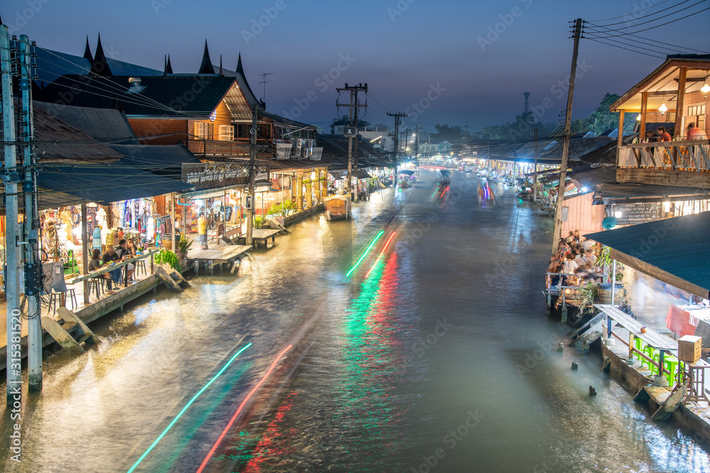 AMPHAWA, THAILAND - DECEMBER 15, 2019: Light trails of boat crossing the river in Amphawa night floating market near Bangkok
