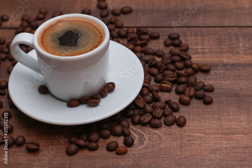 White cup of coffee and beans on brown wooden table. Coffee shop, espresso, high angle, closeup, template