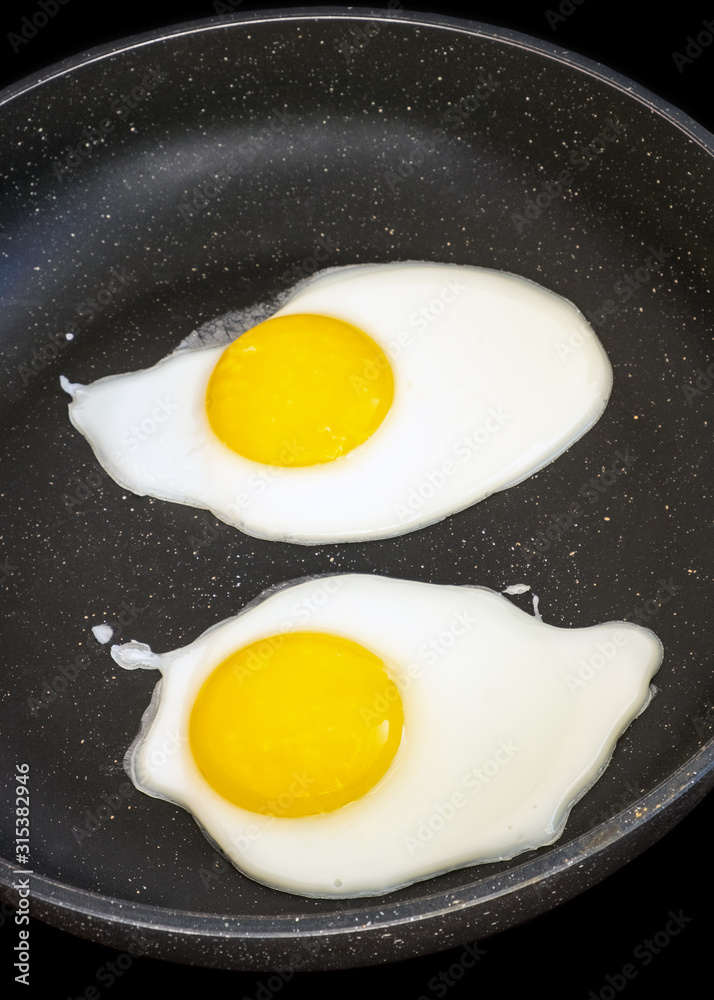 Raw fried eggs.Tasty over easy fried egg in frying pan, closeup Raw fried eggs.Tasty over easy fried egg in frying pan, closeup