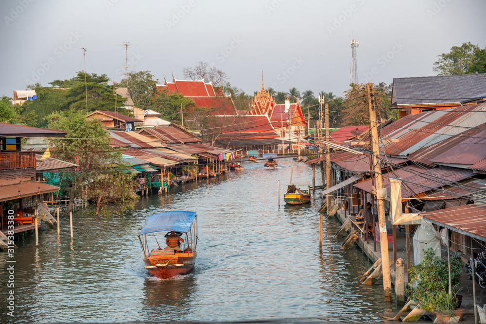 Wooden boats busy ferrying people at Amphawa floating market in Bangkok. A traditional popular method of buying and selling still practiced in Amphawa canals of Thailand