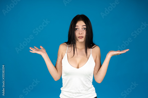 Front view of brunette girl shrugging isolated on blue background
