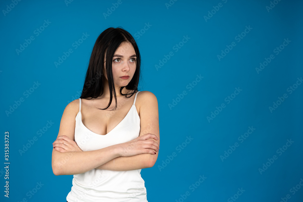 Dreamy beautiful girl looking away with folded arms isolated on blue background Dreamy beautiful girl looking away with folded arms isolated on blue background