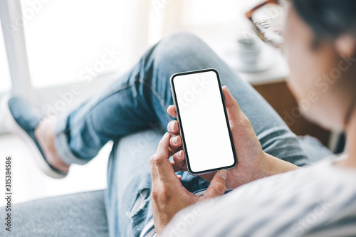 Mockup image blank white screen cell phone.man hand holding texting using mobile sitting at coffee shop.background empty space for advertise text.people contact marketing business,technology 