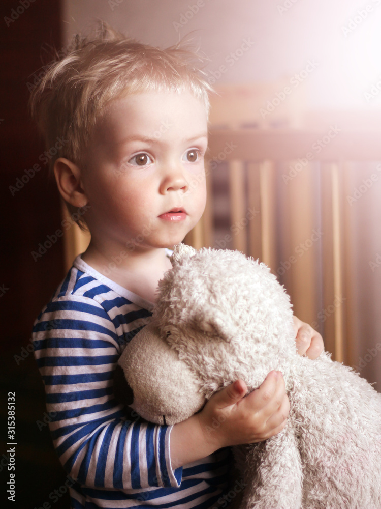 The little blonde boy hugging a soft Teddy bear The little blonde boy hugging a soft Teddy bear