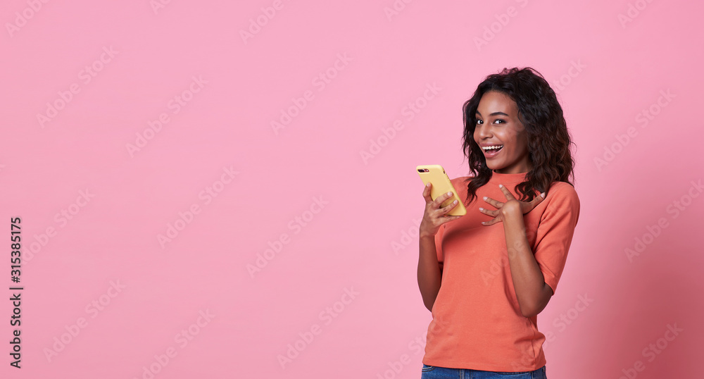 Happy young woman being surprised after reading message from smartphone isolated over pink background. Happy young woman being surprised after reading message from smartphone isolated over pink background.