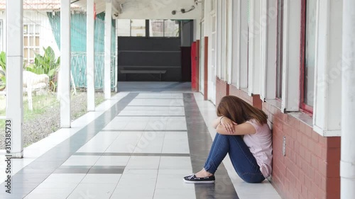 Sad asian girl seating on school hallway, bullying concept