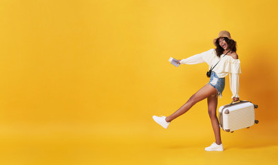Happy smiling african woman dressed in summer clothes with luggage enjoying their summer vacation getaway in yellow banner background with copy space.