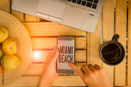 Handwriting text writing Miami Beach. Conceptual photo the coastal resort city in MiamiDade County of Florida woman computer smartphone drink mug office supplies technological devices photo