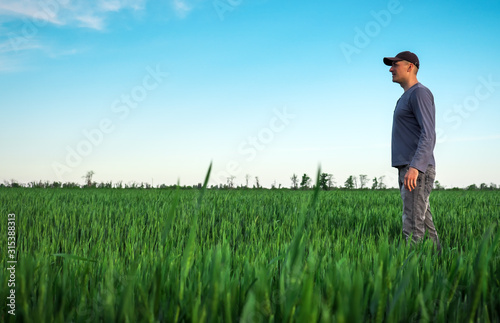 Handsome farmer. Young man walking in green field. Spring agriculture. © es0lex