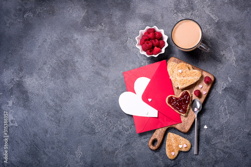 Saint Valentine Day background, heart shaped toast bread with raspberry jam and cup of coffee, place for text , romantic morning