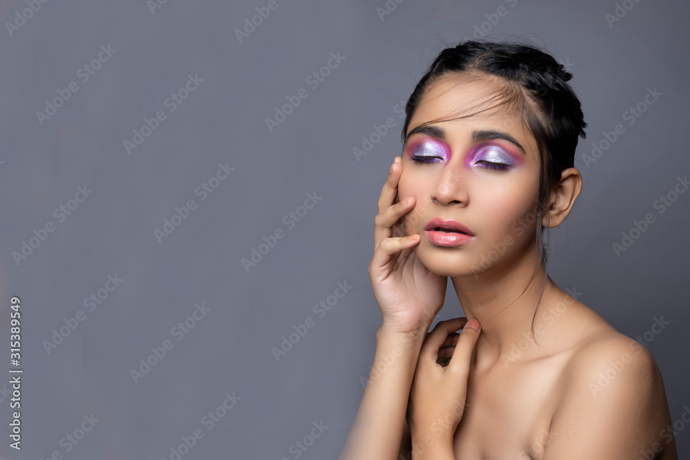 Obraz premium Closeup portrait of an Indian model with bold eye makeup and lipstick looking at camera. Makeup portrait for eye makeup and lipstick.
