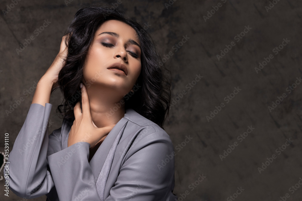 portrait of an Indian female model with eye makeup and glossy dark color lipstick blazer wear nice hair and expression