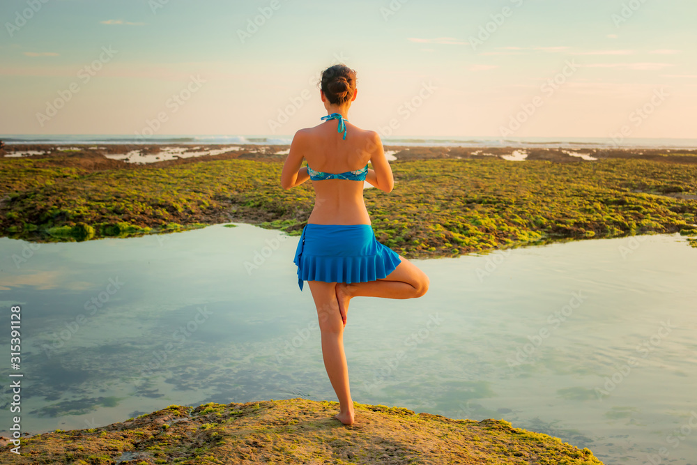 Vrikshasana asana. Young woman practicing tree pose at the beach during ...