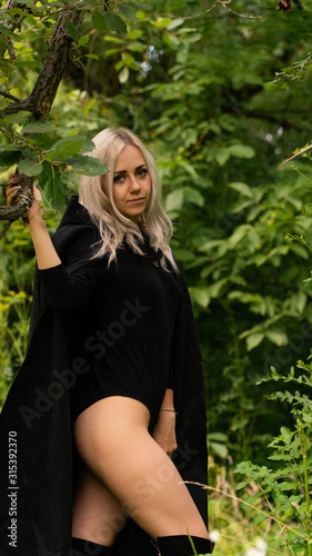 sexy blonde woman in black cloak nature