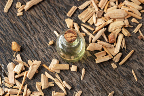 A bottle of cedar essential oil with pieces of cedar wood photo