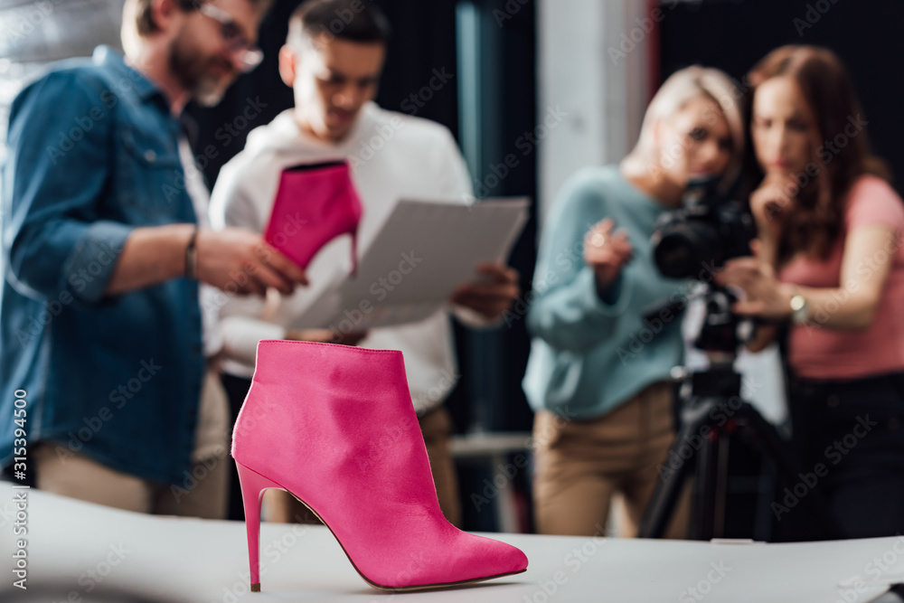 selective focus pink shoe near team in photo studio