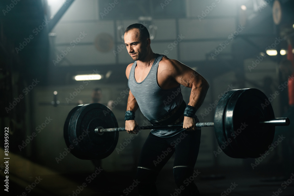 Athletic man making an effort while weightlifting on strength training in a gym.