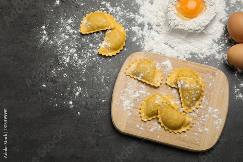 Flat lay composition with raw ravioli on grey table. Italian pasta photo