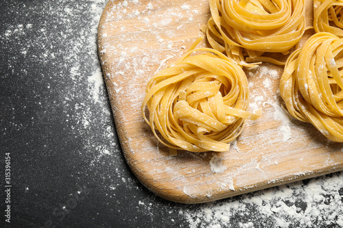Tagliatelle pasta on wooden board, above view