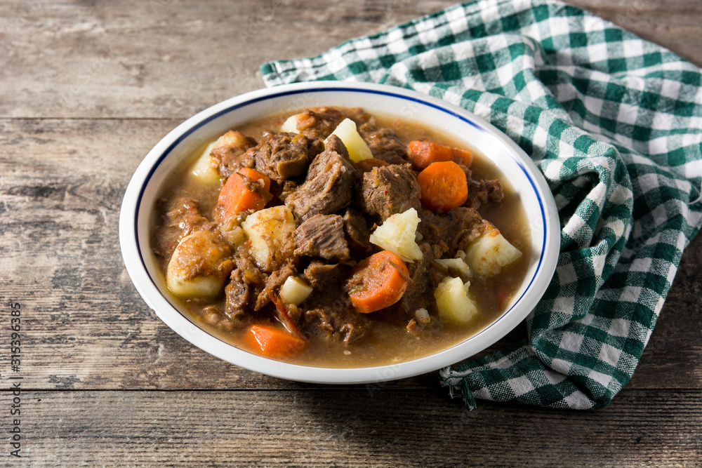 Irish beef stew with carrots and potatoes on wooden table Irish beef stew with carrots and potatoes on wooden table