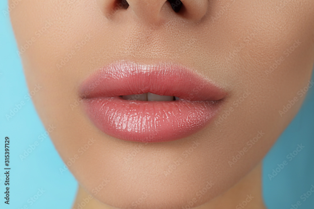 Obraz premium Woman with beautiful full lips on light blue background, closeup