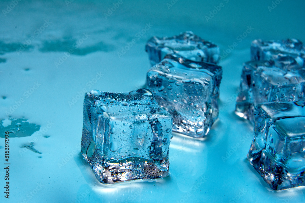 Ice cubes / Ice cubes witha drops of water isolated on blue background / Copy space for text / Close up. Ice cubes / Ice cubes witha drops of water isolated on blue background / Copy space for text / Close up.