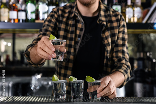 Bartender with shots of Mexican Tequila at bar counter, closeup