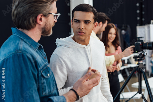 selective focus of handsome assistant looking at art director in glasses